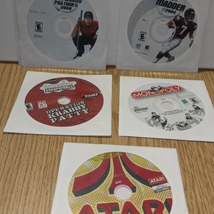 May include: Five video game discs in their cases. The discs are for the games Tiger Woods PGA Tour 2004, Madden NFL 2004, Spongebob Squarepants Operation Krabby Patty, Monopoly, and Atari 50 Classic Games in One.