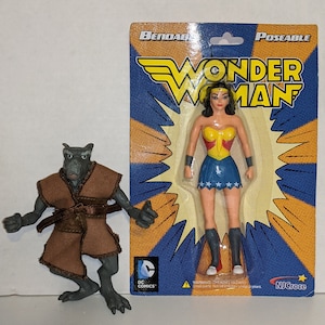 May include: A bendable and poseable Wonder Woman action figure in a blue, yellow, and red package. The figure is wearing a red, blue, and gold costume with a star-spangled skirt. The package also features the DC Comics logo and the text "Bendable Poseable Wonder Woman".