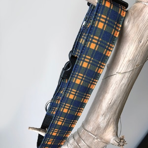 May include: A blue and orange plaid dog collar with a black buckle.