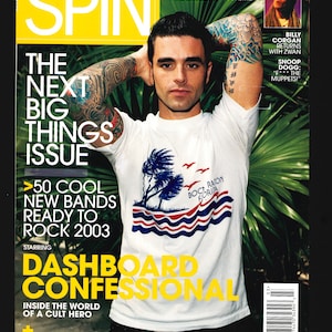 Könnte beinhalten: Ein Magazincover für das Spin Magazin mit einem Mann mit Tattoos auf den Armen, der ein weißes T-Shirt mit einem Palmenmotiv und den Worten "Boca Raton Florida" trägt. Der Titeltext lautet "The Next Big Things Issue" und "50 Cool New Bands Ready to Rock 2003".