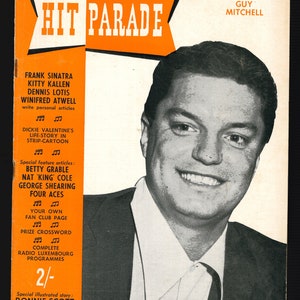 May include: A vintage magazine cover from February 1955, featuring a black and white portrait of Guy Mitchell. The title "HIT PARADE" is in bold white letters on an orange background. Additional text lists articles and features.
