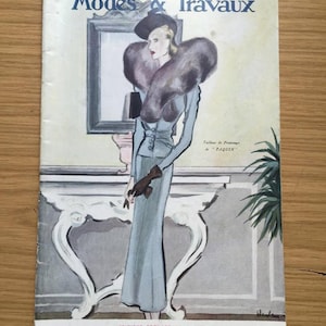 May include: A vintage magazine cover featuring a woman in a light blue dress and a fur collar. The magazine is titled "Modes & Travaux" and the text "Tailleur de Printemps de "PAQUIN" is visible. The cover is dated "1er Mars 1938."