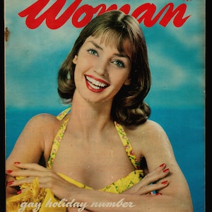 May include: A woman in a yellow swimsuit smiles at the camera. The cover of a magazine titled "Woman" is behind her. The magazine cover text reads "World's Greatest Weekly for Women" and "Gay Holiday Number".