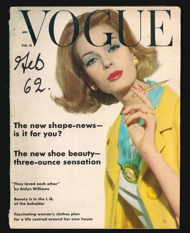 May include: Vogue magazine cover from February 15, 1962, featuring a woman in a yellow jacket and blue scarf, holding a pen. The text on the cover reads "The new shape-news - is it for you?" and "The new shoe beauty - three-ounce sensation."