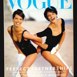 Könnte beinhalten: Vogue-Magazin-Cover mit zwei Frauen in schwarzen Badeanzügen am Strand. Der Titeltext lautet "Perfect Partnerships" und "Summer Hats, Softest Suits: Shimmering Beauty: The Power of Black and White."