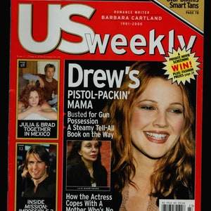 May include: US Weekly magazine cover featuring Drew Barrymore with the headline "Drew's Pistol-Packin' Mama". The sub-headline reads "Busted for Gun Possession. A Steamy Tell-All Book on the Way".