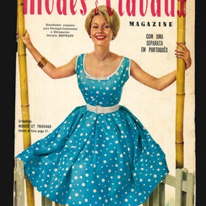 May include: A vintage magazine cover featuring a woman in a blue polka dot dress, holding onto two bamboo poles. The magazine is titled "Modes & Travau" and is a June 1959 issue.