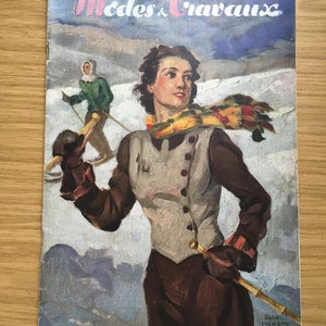 May include: A vintage magazine cover featuring a woman in a brown vest and a colorful scarf, skiing down a snowy mountain. The magazine is titled "Modes & Travaux" and is dated December 1938.