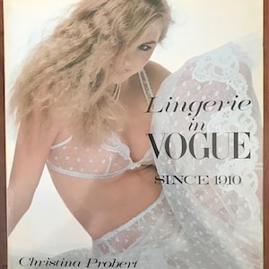 May include: A book cover featuring a woman wearing a white lace lingerie set. The title of the book is "Lingerie in Vogue Since 1910" and the author is Christina Probert.