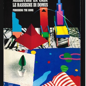 以下が含まれることがあります： 「ALLESTIRE LA CASA」と「FURNISHING THE HOME」というタイトルの雑誌の表紙。赤、青、黄色の構造物や赤いピラミッドなど、カラフルな幾何学模様が特徴です。背景は黒、白、青が混ざっています。