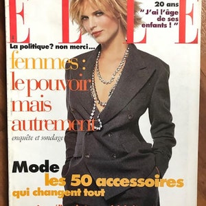 May include: A magazine cover featuring a woman wearing a grey blazer and a pearl necklace. The magazine is titled "ELLE" and the cover story is "Women: The Power, But Differently".