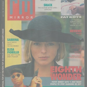 Puede incluir: Una portada de revista para Record Mirror, con una foto de una mujer con un sombrero negro y una camisa blanca. La portada también presenta fotos de un hombre con un micrófono y un hombre con un afro grande. El texto en la portada incluye el título "Record Mirror", los nombres "Sabrina", "Elisa Fiorillo", "Fat Boys", "Eighth Wonder", y "KRS-One".