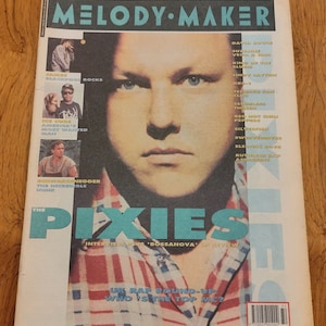 Op de afbeelding: Een vintage exemplaar van het Melody Maker magazine van 11 augustus 1990, met een portret van een man op de cover. De titel van het tijdschrift staat in vette, blauwe en witte letters. De cover bevat ook tekst over The Pixies en andere muziekkunstenaars.