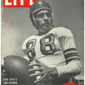 Puede incluir: Una fotografía en blanco y negro de un jugador de fútbol americano que lleva una camiseta blanca con el número 88. El jugador está sosteniendo un balón de fútbol y mirando a la cámara. La foto es de la edición del 22 de octubre de 1945 de la revista LIFE.
