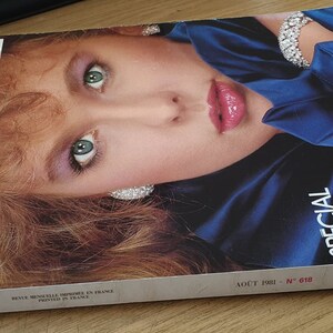 May include: A vintage Vogue Paris magazine cover from August 1981, featuring a woman with long red hair wearing a blue satin top and a diamond necklace. The cover text reads "Special Pret-a-Porter".