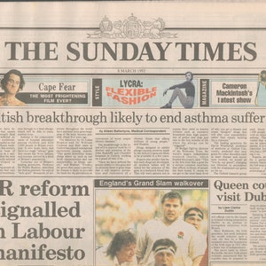 Peut inclure: Une page de journal en noir et blanc avec le titre "British breakthrough likely to end asthma suffering". L'article traite d'un nouveau traitement contre l'asthme. Le journal présente également une photo d'un joueur de rugby portant un maillot blanc avec le titre "England's Grand Slam walkover".