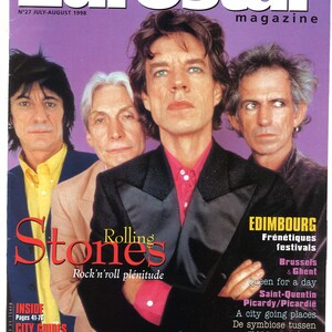 Pode incluir: Uma capa de revista com uma foto dos membros da banda Rolling Stones. A capa é roxa e apresenta o nome da banda em letras vermelhas grandes. O texto "Rock 'n' roll plénitude" está abaixo do nome da banda. A revista é intitulada "Eurostar" e é datada de julho-agosto de 1998.