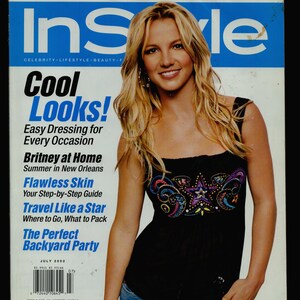 May include: A magazine cover featuring a woman with blonde hair wearing a black tank top with a colourful star design. The magazine is titled "InStyle" and the cover headline is "Cool Looks!" with the subheading "Easy Dressing for Every Occasion".