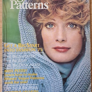 May include: A vintage Vogue Patterns magazine cover showing a woman with blue eyes and a light blue knitted hood. The cover includes text such as "Get a Big Start into Fashion '75" and "The Bigsweater!"