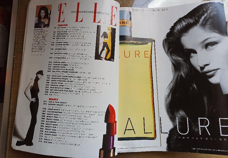 May include: A magazine spread featuring a black and white photo of a woman with long hair and a close-up of a bottle of perfume with the word "ALLURE" printed on the label. The magazine is titled "ELLE" and features a list of fashion and beauty articles.