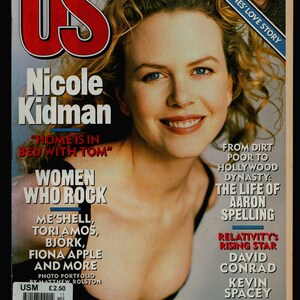 Op de afbeelding: US magazine cover met actrice Nicole Kidman. De cover bevat de tekst "HOME IS IN BED WITH TOM" en "WOMEN WHO ROCK" met namen van vrouwelijke muzikanten. Extra tekst omvat "RALPH FIENNES' LOVE STORY" en "FROM DIRT POOR TO HOLLYWOOD DYNASTY".