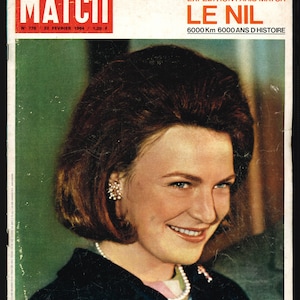 Könnte beinhalten: Ein Magazincover mit einer Frau mit kurzen braunen Haaren und einer weißen Perlenkette. Das Magazin heißt "Paris Match" und die Titelgeschichte handelt von einer Nil-Expedition. Der Text auf dem Cover lautet: "EXCEPTIONNEL 24 PAGES COULEURS UNE GRANDE EXPEDITION PARIS MATCH LE NIL 6000 Km 6000 ANS D'HISTOIRE".