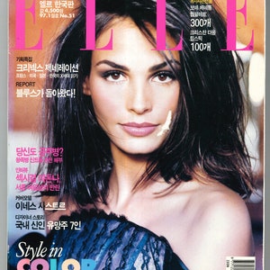 May include: A magazine cover featuring a woman with dark hair and a blue and black lace top. The magazine is titled "ELLE" and the cover text includes "Style in Color" and "Red & Pink, Green, Yellow, Camel & Grey, Blue... 8 ways to style with color".