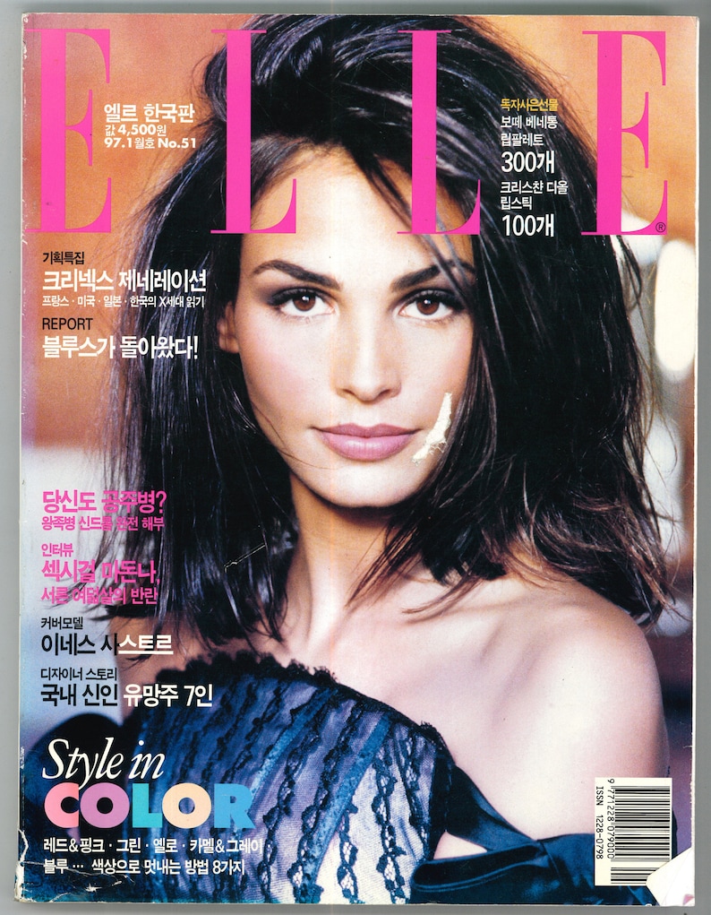 May include: A magazine cover featuring a woman with dark hair and a blue and black lace top. The magazine is titled "ELLE" and the cover text includes "Style in Color" and "Red & Pink, Green, Yellow, Camel & Grey, Blue... 8 ways to style with color".