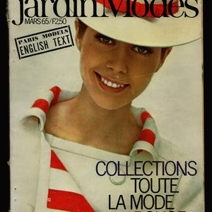 May include: A magazine cover featuring a woman wearing a white hat with a red stripe. The magazine is titled "Jardin des Modes" and the cover text reads "Paris Models English Text" and "Collections Toute La Mode Bouge".