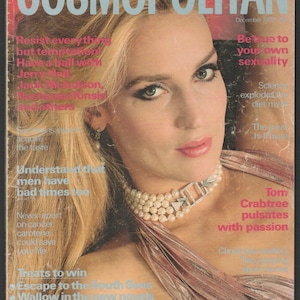 以下が含まれることがあります： 1982年12月号のCosmopolitan誌の表紙。ブロンドの髪の女性が、真珠のネックレスとピンクのドレスを着ています。雑誌のタイトルは薄い青色の文字で表示されています。