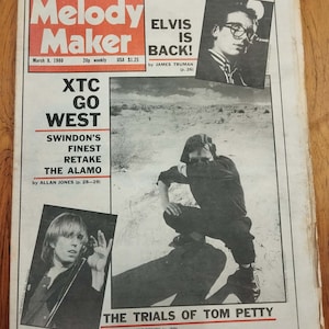 Può includere: Una copertina di rivista in bianco e nero con il titolo "Melody Maker" e il testo "Elvis is Back!" La copertina presenta una foto di un uomo con gli occhiali e una foto di un uomo in un ambiente desertico.