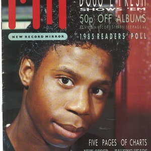 May include: A close-up of a young man's face, looking to the side. He has short, dark hair and is wearing a black leather jacket. The image is from a magazine cover, with the text "Doug E Fresh Shows 'Em 50p Off Albums" and "1985 Readers' Poll" visible.
