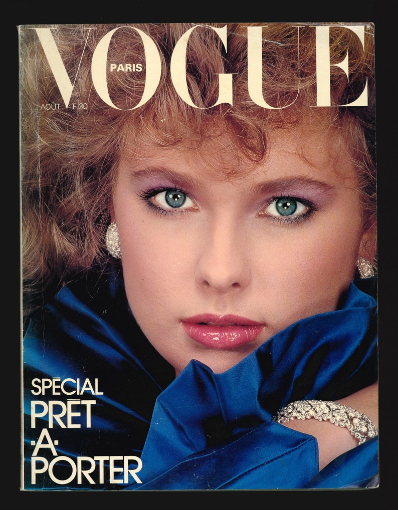 May include: A vintage Vogue Paris magazine cover from August 1980 featuring a woman with blue eyes and a blue satin top. The cover text reads "SPECIAL PR&Ecirc;T-&Agrave;-PORTER".