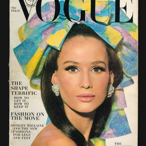 Pode incluir: Uma capa de revista Vogue vintage com uma mulher de cabelo escuro e uma faixa de cabeça floral. O texto da capa diz "The Shape Terrific How to Get It... How to Keep It Fashion on the Move Shirley Maclaine and the New Fashions for Legs and Feet The Beautiful People".