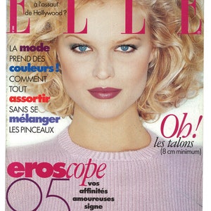 May include: A magazine cover featuring a woman with blonde hair and a pink sweater. The magazine is titled "ELLE" and the cover text reads "Oh! les talons (8 cm minimum)".