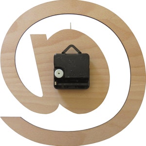 May include: A wooden clock with an @ symbol design. The clock is made of light wood and has a black clock mechanism on the back.