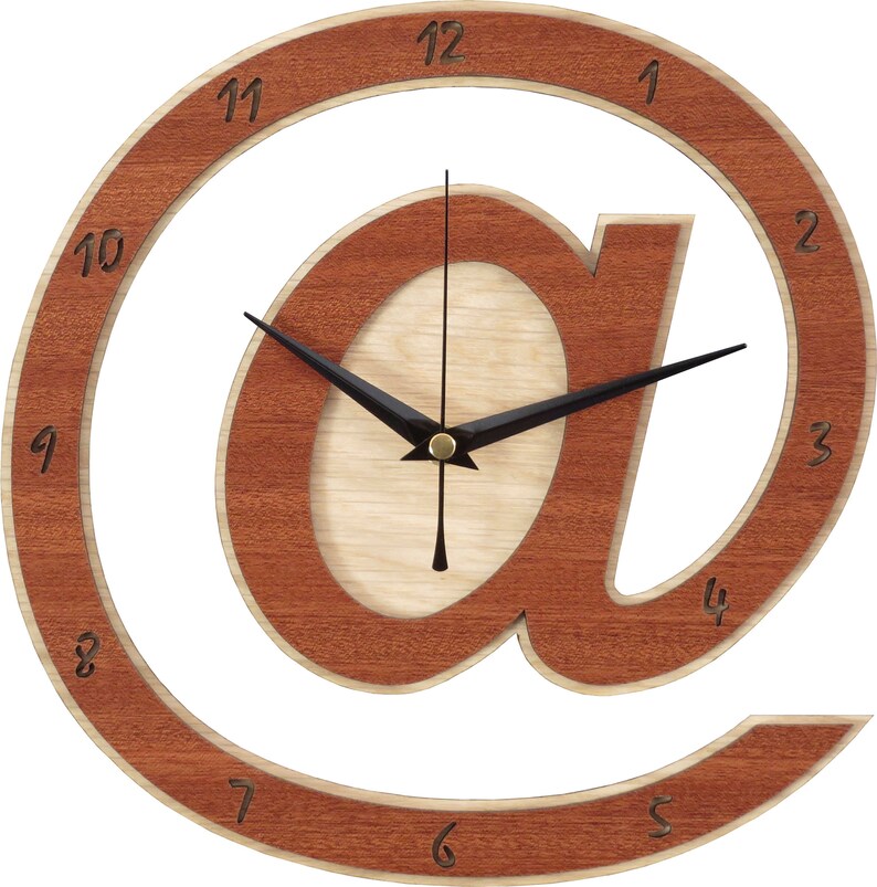 May include: A wooden wall clock shaped like the "@" symbol. The clock face is made of light wood and the numbers are in a dark wood. The hands are black.