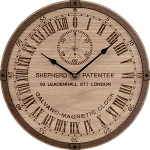 Pode incluir: Um mostrador de relógio de madeira com algarismos romanos e um mostrador de relógio menor no seu interior. O mostrador de relógio maior diz 'SHEPHERD PATENTEE 53 LEADENHALL STI LONDON GALVANO-MAGNETIC CLOCK'.