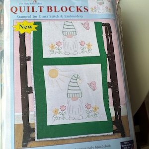 May include: A package of quilt blocks for hand embroidery. The package features two embroidered gnome designs with flowers, butterflies, and a sun. The blocks are 18" x 18" and made of cotton/poly broadcloth. The package is labeled "New".