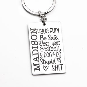 May include: Silver keychain with the name "MADISON" engraved vertically on the left side of a rectangular tag. The tag has the text "Have Fun! Be Safe. Wear your Seatbelt, & Don't Do Stupid SHIT" engraved on the right side.
