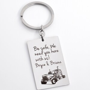 May include: Silver keychain with a rectangular tag that says "Be safe, We need you here with us! Bryce & Briana" and a black and white image of a semi-truck.