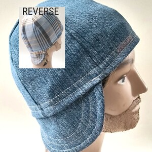 May include: A blue denim welding cap with white stitching and a curved brim. The cap features a structured crown and side flaps. An inset image labeled REVERSE shows the back of the cap, which has a blue, white, and tan plaid fabric pattern.