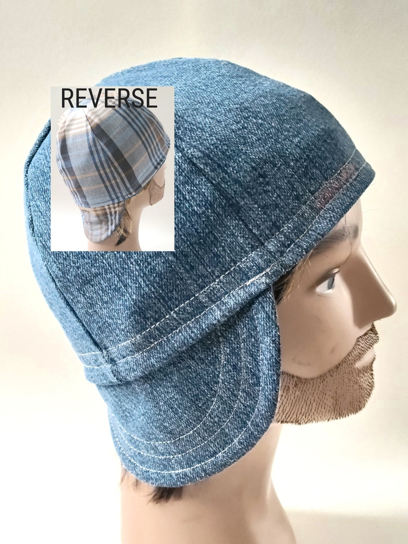 May include: A blue denim welding cap with white stitching and a curved brim. The cap features a structured crown and side flaps. An inset image labeled REVERSE shows the back of the cap, which has a blue, white, and tan plaid fabric pattern.