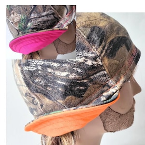 May include: Camouflage print beanie with a bright orange brim. The beanie has a contrasting pink brim on the other side.