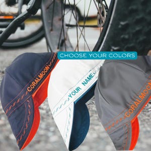 May include: Three welding caps in navy blue, white, and gray, each featuring orange or teal stitching and text. The navy cap reads CORALMOON, the white cap reads YOUR NAME, and the gray cap reads CORALMOON. The text CHOOSE YOUR COLORS is visible.