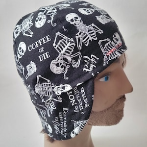 May include: A black scrub cap featuring a white skeleton print and text that reads COFFEE OR DIE, Life begins after coffee, and Don't talk to me until I've had my coffee. The fabric also includes the text I am NOT a morning person.
