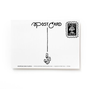 May include: A blank white postcard with black ink. The postcard has the words "POSTCARD" written at the top and a line drawn down the center. There is a small black and white stamp in the upper right corner that says "PLACE STAMP HERE". The bottom of the postcard has the text "PEPPERCORN PAPER - www.peppercornpaper.com - MADE IN THE USA - PC004".