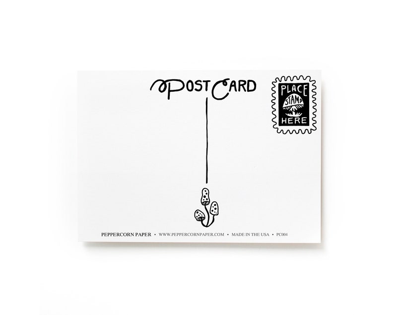 May include: A blank white postcard with black ink. The postcard has the words "POSTCARD" written at the top and a line drawn down the center. There is a small black and white stamp in the upper right corner that says "PLACE STAMP HERE". The bottom of the postcard has the text "PEPPERCORN PAPER - www.peppercornpaper.com - MADE IN THE USA - PC004".