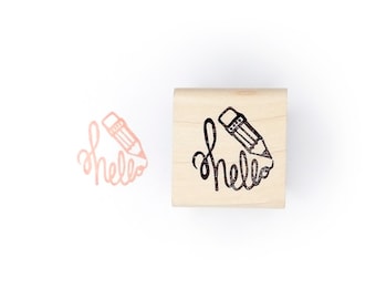 May include: A wooden stamp with the word "hello" written in cursive with a pencil drawing a line through the word.