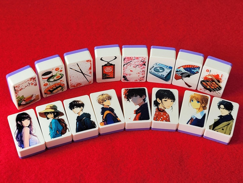 May include: A set of 14 white tiles with purple trim, each featuring a different design. Some tiles have illustrations of anime characters, while others have images of food, flowers, and other objects. The tiles are arranged in a row on a red surface.